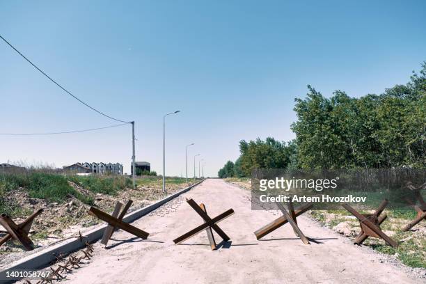 several czech hedgehogs crossing a road, outside of big city - ukraine war foto e immagini stock