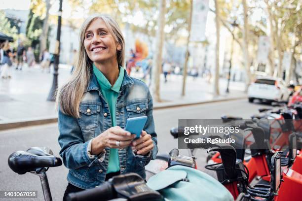reife frau im urlaub, die ein e-bike mietet - mobility as a service stock-fotos und bilder