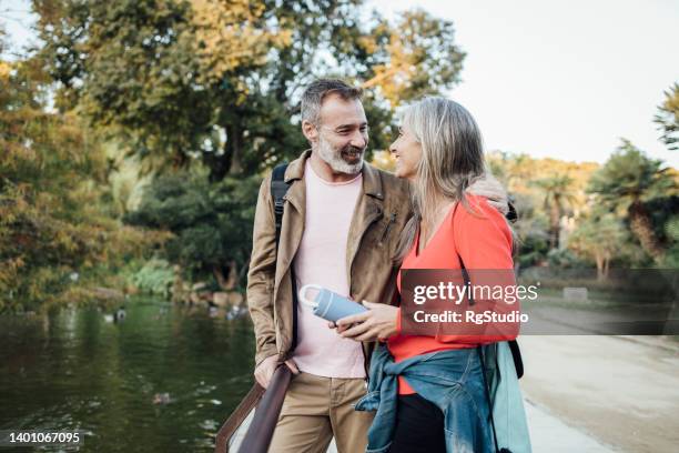 happy mature couple enjoying their vacation and taking a break by the river - mature adult couple stockfoto's en -beelden