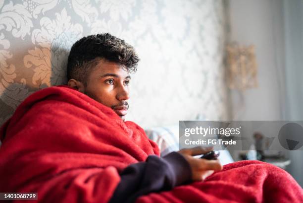 young man lying down watching tv at home - lazy sunday stock pictures, royalty-free photos & images