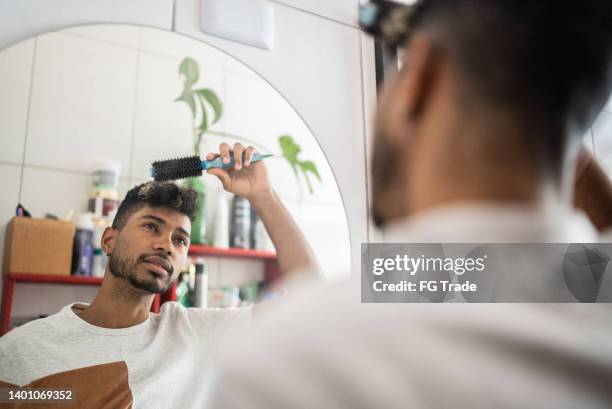 young man brushing hair with comb at bathroom - man combing hair stock pictures, royalty-free photos & images