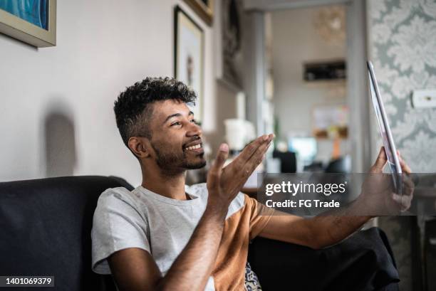 young man doing a video call using digital tablet at home - misses vlog stock pictures, royalty-free photos & images