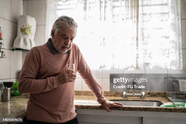 senior man feeling pain at home - hispanic person sick 個照片及圖片檔