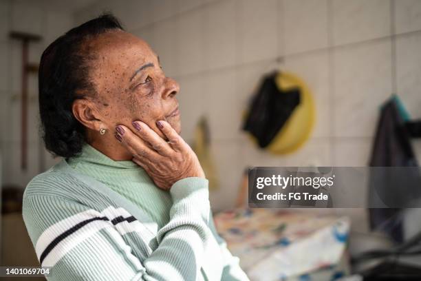 contemplative senior woman looking away at home - chronic condition stock pictures, royalty-free photos & images