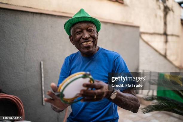 senior man playing tambourine at home - brazilian music stock pictures, royalty-free photos & images