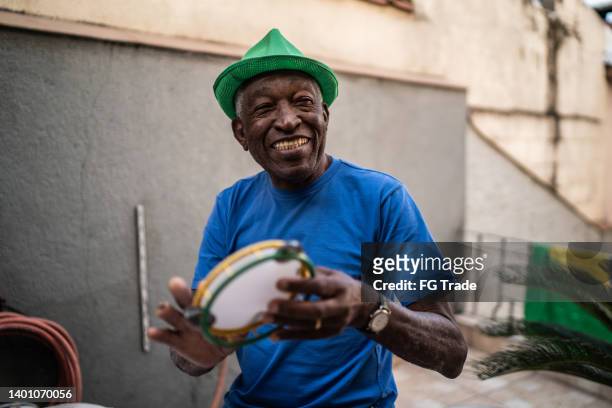 senior man playing tambourine at home - tambourine 個照片及圖片檔