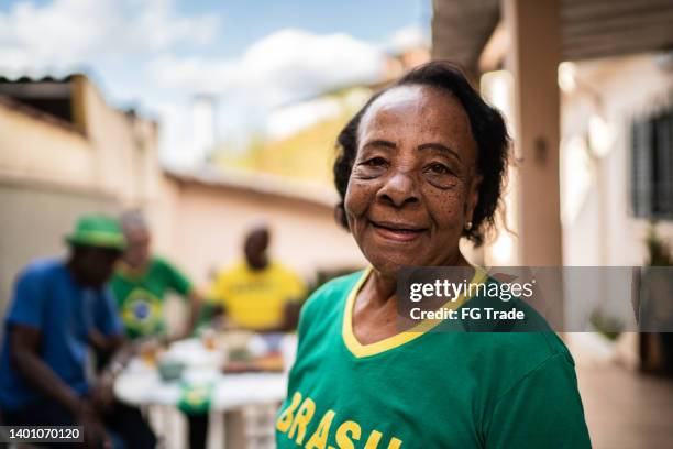 porträt einer älteren frau zu hause mit freunden - fußball fan oma stock-fotos und bilder