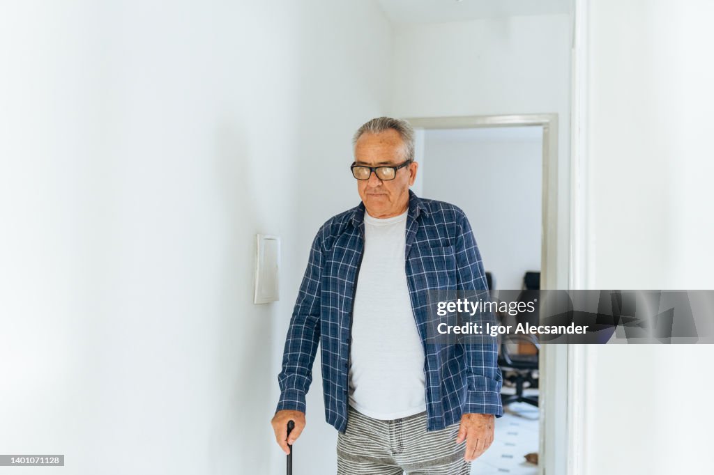 Idoso andando em casa com bengala