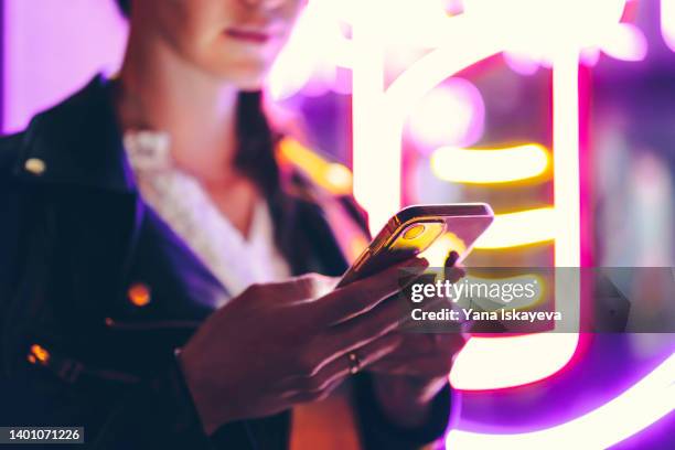 progressive woman is using mobile phone at night in neon lights - white smart phone stock pictures, royalty-free photos & images