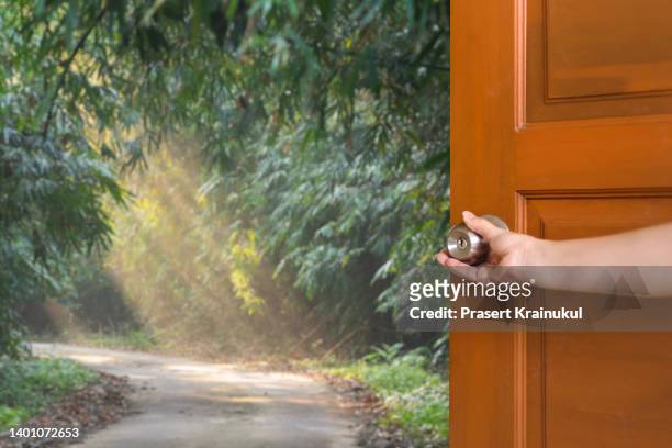 hand at home opening the wooden door with view on footpath through natural green forest - sun rays through window stock pictures, royalty-free photos & images