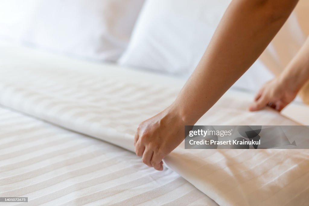 Housekeeper set of white bed linens in bedroom. Hotel concept