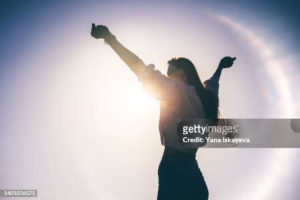 happy woman silhouette against sunset - survivor stockfoto's en -beelden