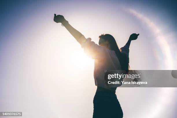 happy woman silhouette against sunset - arms raised to sky stock pictures, royalty-free photos & images