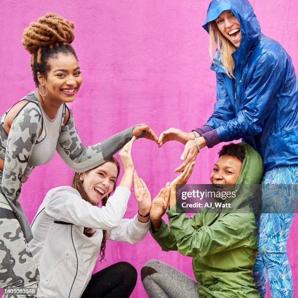 smiling multiracial female friends making a heart shape with their hands - doing a favour stock pictures, royalty-free photos & images