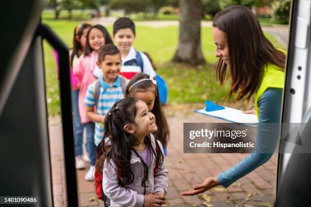 assistant teacher helping students while boarding the school bus - school bus kids stock pictures, royalty-free photos & images