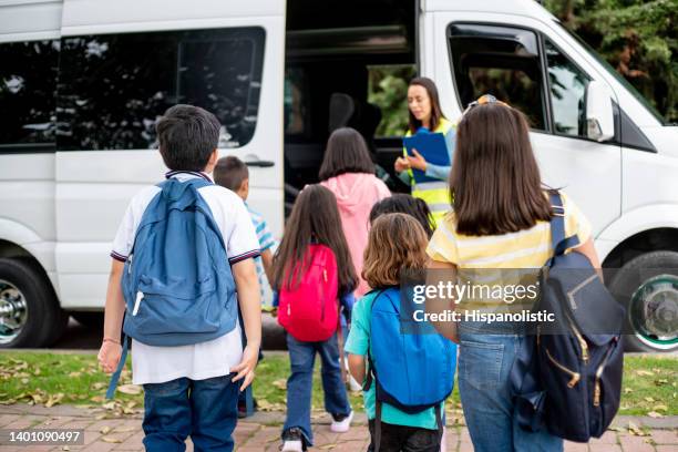 teacher supervising a group of children boarding the school bus - bestelwagen stockfoto's en -beelden