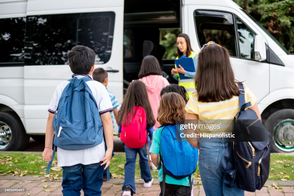 Teacher supervising a group of children boarding the school bus