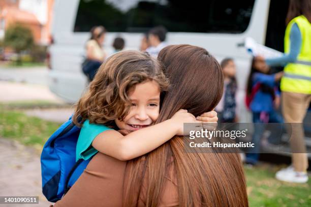 boy greeting his mother with a hug while she is picking him up from school - first day school hug stock pictures, royalty-free photos & images