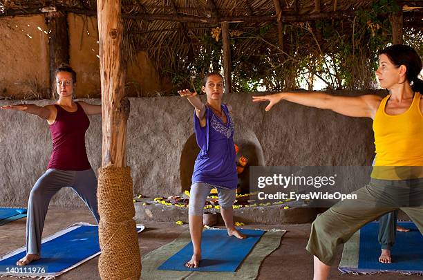 Yoga female tourists practice yoga postures and asanas like padmasana, lotus pose,in a traditional yoga shala at Yoga Magic Eco Retreat in Anjuna on...