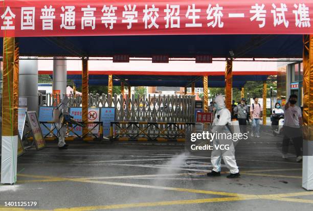 Volunteer wearing personal protective equipment sprays disinfectant at an exam site ahead of China's national college entrance exam on June 5, 2022...