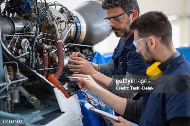 mecánicos e ingenieros de aeronaves en el hangar - aerospace industry fotografías e imágenes de stock