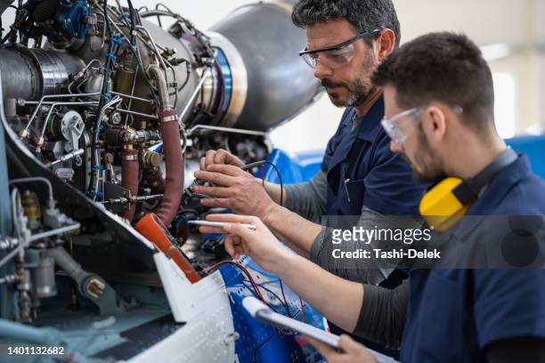 aircraft mechanics and engineers in the hangar - aerospace industry imagens e fotografias de stock