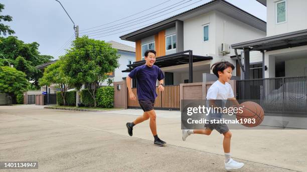 happy father and son playing with a basket ball at their backyard - hitting home run stock pictures, royalty-free photos & images