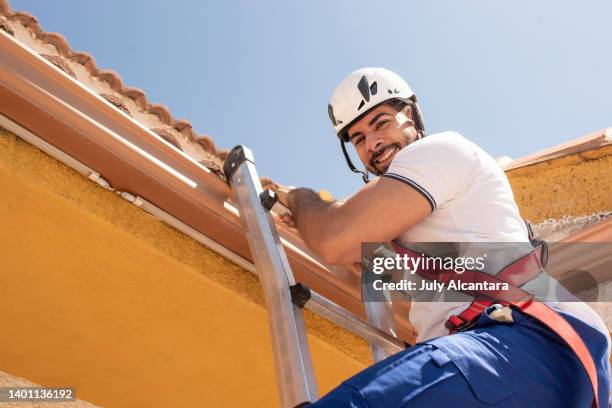 installation of solar panels on the roof of a house, man climbing staircase smiling - roupa desportiva de protecção imagens e fotografias de stock