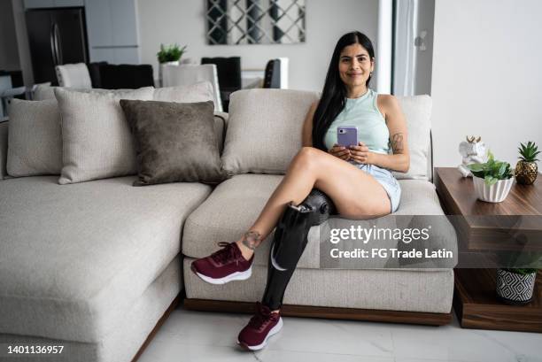 portrait of disabled young woman using mobile phone at home - amputee women stockfoto's en -beelden