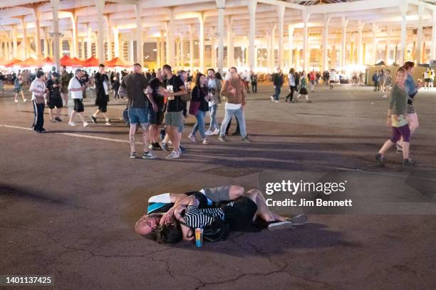 Two people cuddle on the pavement as the crowd walks by during Primavera Sound on June 4, 2022 in Barcelona, Spain.