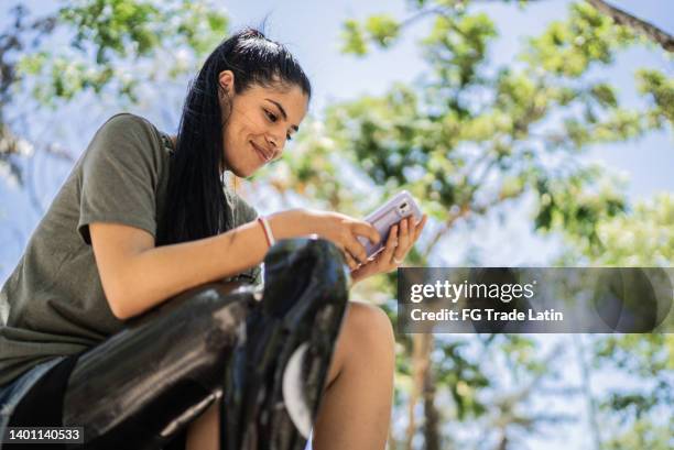 disabled woman using mobile phone at the park - amputee stock pictures, royalty-free photos & images