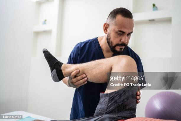 physiotherapist giving therapy to patient at medical clinic - human joint stock pictures, royalty-free photos & images