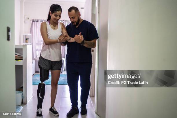 behinderte mittelerwachsene frau, der von einem physiotherapeuten geholfen wird - amputiert stock-fotos und bilder