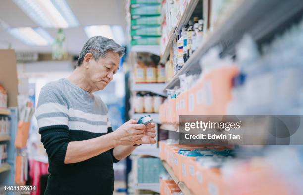asiático chino anciano que busca suministros médicos en la farmacia de la farmacia - material médico fotografías e imágenes de stock