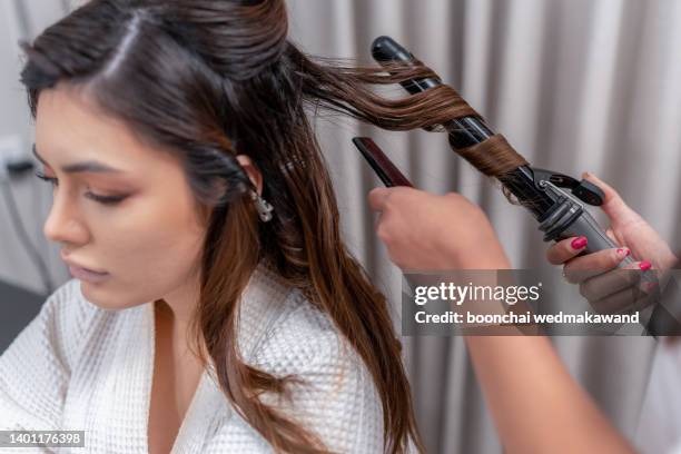 hairdresser using a curling iron. - black hair stylist stock pictures, royalty-free photos & images