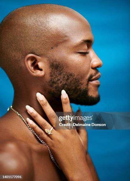 closeup of an african man with a female hand touching his face while standing against a blue background - bald man stockfoto's en -beelden