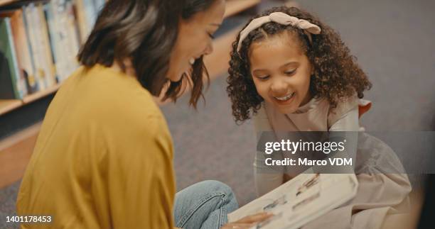 teacher and student inside a library alone. young females reading a book together. cute girl with curly hair doing her project with her teacher - choosing a book stock pictures, royalty-free photos & images
