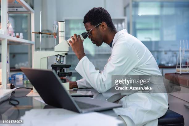 african-american man looking in microscope - biologist stock pictures, royalty-free photos & images