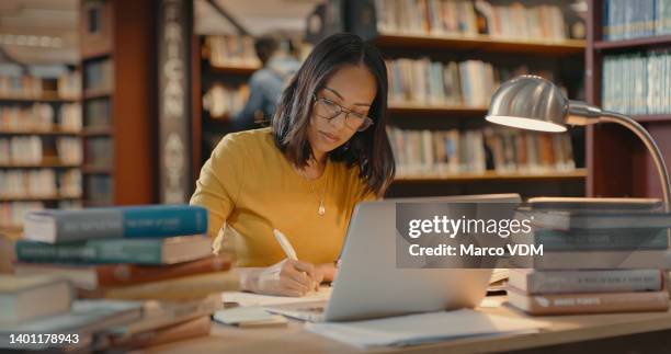 young lady using a laptop to do research on the internet. woman working on a project. mixed race woman sending emails. - bibliotheek stockfoto's en -beelden