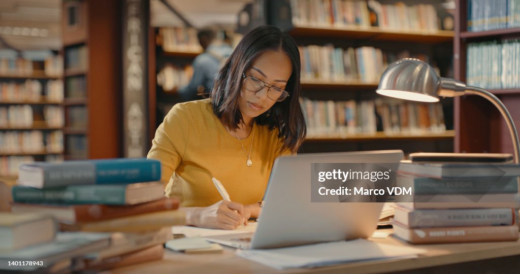Young lady using a laptop to do research on the internet. Woman working on a project. Mixed race woman sending emails.