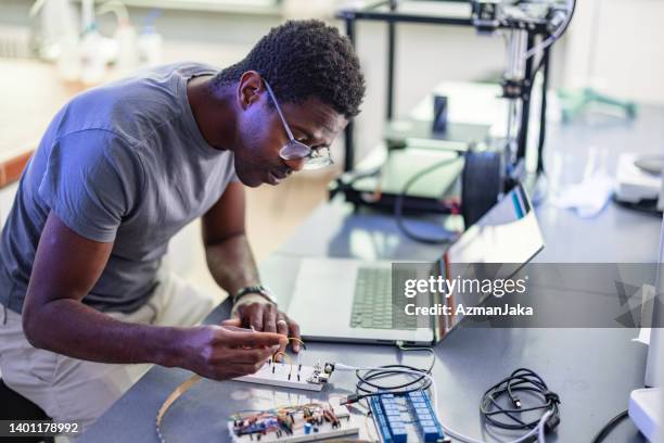 african-american technician repairing a 3d printer in laboratory - prototype stock pictures, royalty-free photos & images