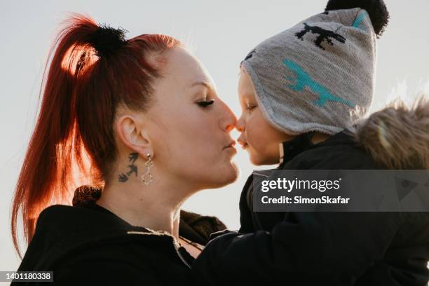 mother rubbing nose with little baby boy against sky - mom-and-son-tattoo-designs stock pictures, royalty-free photos & images