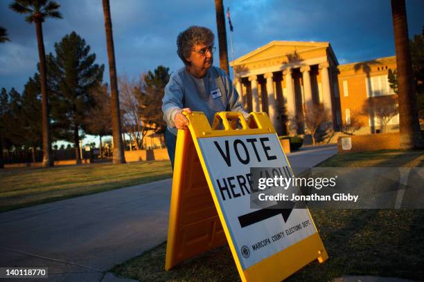 Election day volunteer Vicki Groff places a sign to direct voters to a polling station at Kenilworth School February 28, 2012 in Phoenix, Arizona....