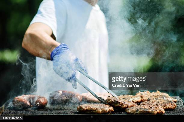 cook grilling sausages - broiling stock pictures, royalty-free photos & images