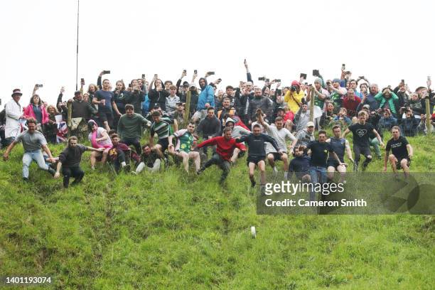 Contestants in the men's downhill race chase the cheese down the hill on June 05, 2022 in Gloucester, England. The Cooper's Hill Cheese-Rolling and...