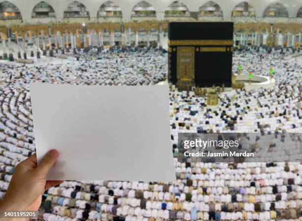 man in front of kaaba in mecca holding blank paper for your text - masjid al haram stock pictures, royalty-free photos & images