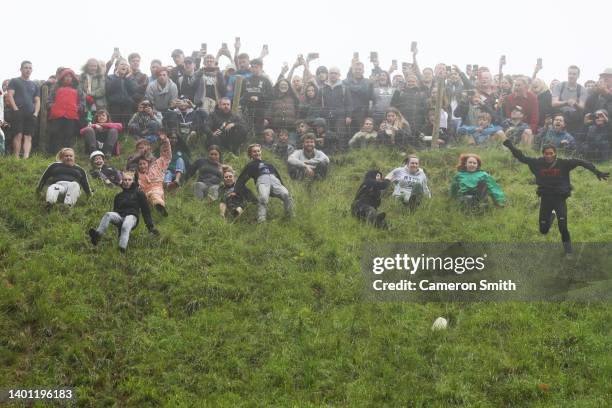 Contestants in the women's downhill race chase the cheese down the hill race during Gloucestershire's famous Cheese-Rolling contest on June 05, 2022...