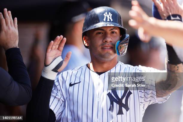 Gleyber Torres of the New York Yankees high-fives teammates after scoring on a bases-loaded walk during the seventh inning against the Detroit Tigers...