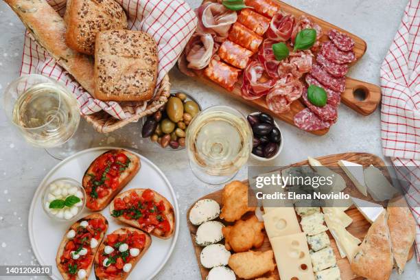 food antipasto prosciutto ham, salami, olives and grissini bread sticks. cheese on a board parmesan, pecorino, gorgonzola. charcuterie board. two glasses of white wine or prosecco - cheese board imagens e fotografias de stock