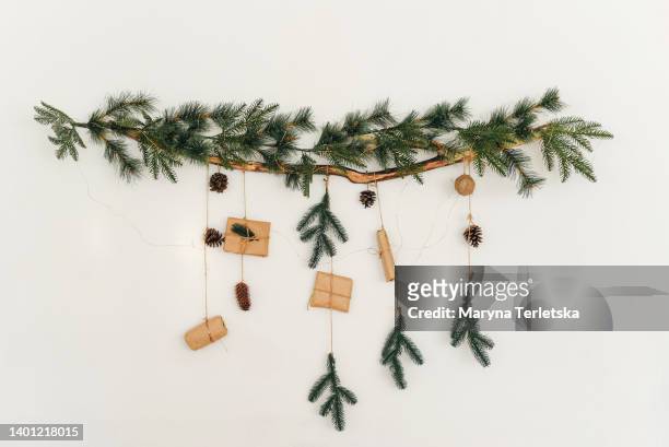 christmas tree branch with a garland and gifts on the wall. new year. christmas. christmas decor. christmas tree. christmas background. holiday. - stylish stockfoto's en -beelden